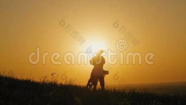 浪漫的男人跪在膝盖上向高山上的女人求婚的剪影-夫妻在日落时订婚
